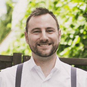 a smiling man with trees in the background